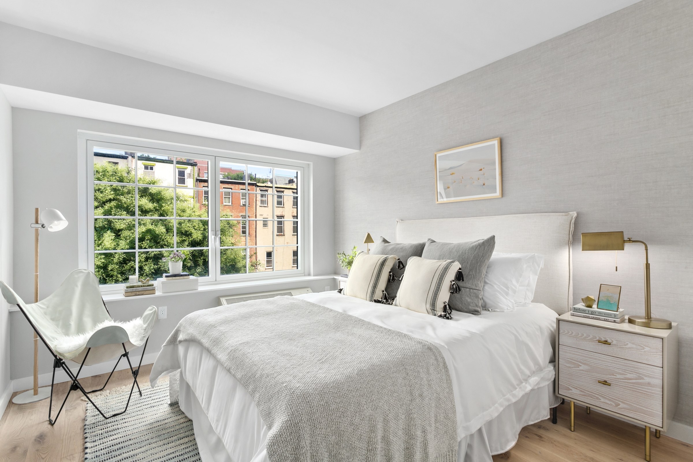A bedroom with a bed, two side tables and a reading chair in a 555 Waverly unit